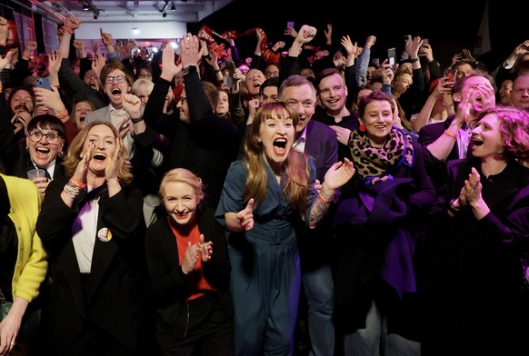 epaselect epa11919326 Heidi Reichinnek (C), top candidate for the Left Party (Die Linke), co-leaders Jan van Aken (C-R) and Ines Schwerdtner (C-L), react with party members to initial results during t ...