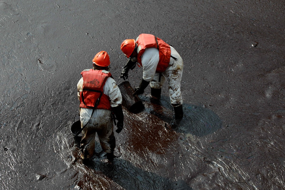 epa09709354 Workers carry out a cleaning operation on the beaches of Ventanilla, Peru, 25 January 2022. The Repsol company stated that it is 'closely collaborating' with civil society and th ...