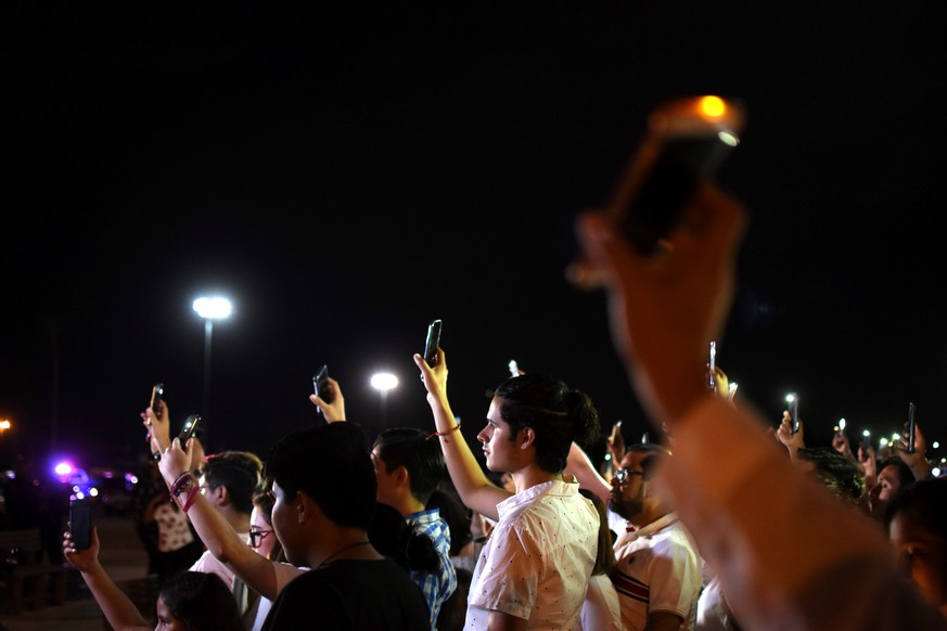 Mexikanische Bürger halten an der US-amerikanischen Grenze zum Gedenken an die Opfer von El Paso ihre leuchtenden Handys in die Luft.