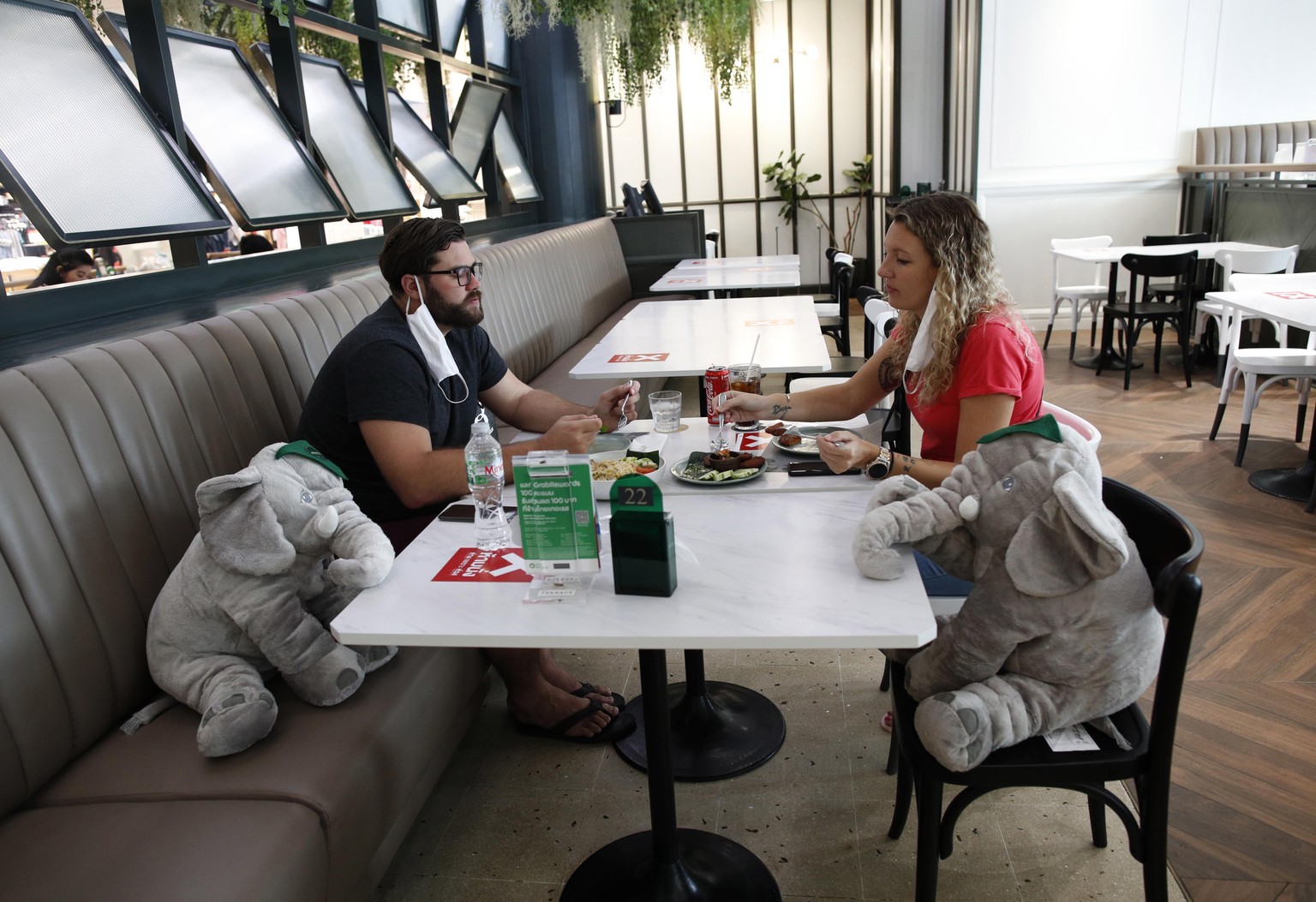 epa08442599 Customers enjoy a meal next to elephant dolls at Thai Terrace restaurant in Bangkok, Thailand, 25 May 2020. The dolls were placed in specific seats in order for people to abide by social d ...