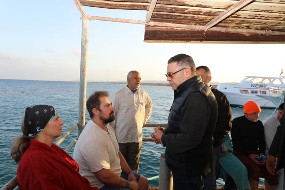 epa11740209 A handout picture made avaliable by Egyptian Press Center shows Red Sea governor Amr Hanafi (L) speaks to survivors after a boat sank at a harbour in Marsa Alam, Red Sea Governorate, in Eg ...