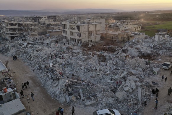 People walk past collapsed buildings after a devastating earthquake hit the town of Jinderis, Aleppo province, Syria, Thursday, February 9, 2023. The earthquake that flattened thousands of buildings was one of the…