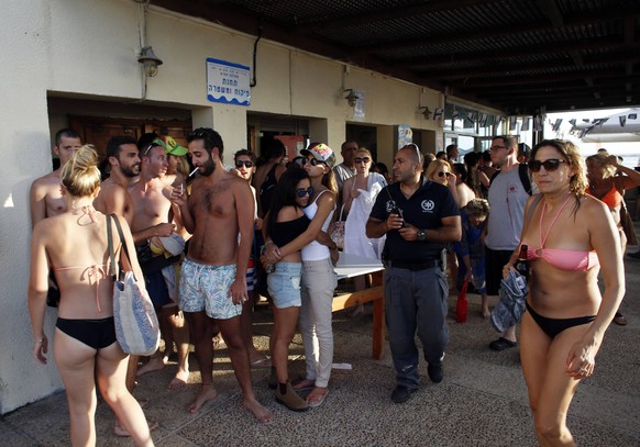Strandgäste in Israel gehen in Schutz, als die Sirenen ertönen.