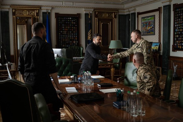 In this photo provided by the Ukrainian Presidential Press Office, Ukrainian President Volodymyr Zelenskyy, center, shakes hands with new commander-in-chief of Ukraine's Armed Forces Mykhailo Dra ...