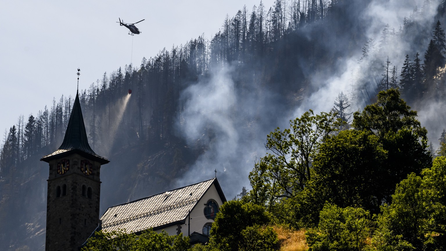 Un helicoptere de la compagnie Air Zermatt, verse de l&#039;eau pour eteindre les foyers dans la foret au-dessus des communes de Bitsch et Ried-Moerel le jeudi 20 juillet 2023 depuis Moerel Filet. Six ...