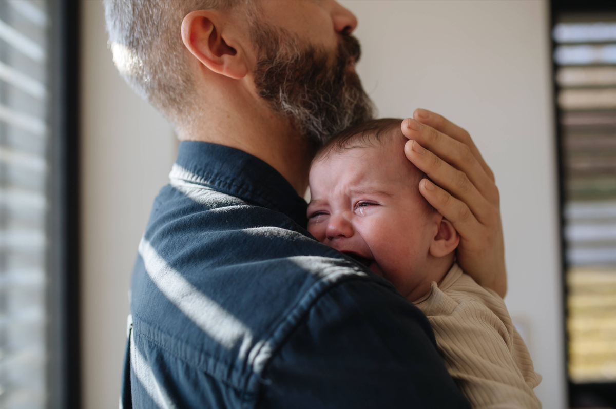 Father comforting his crying baby son. Father comforting his crying baby son, holding him in arms. model released