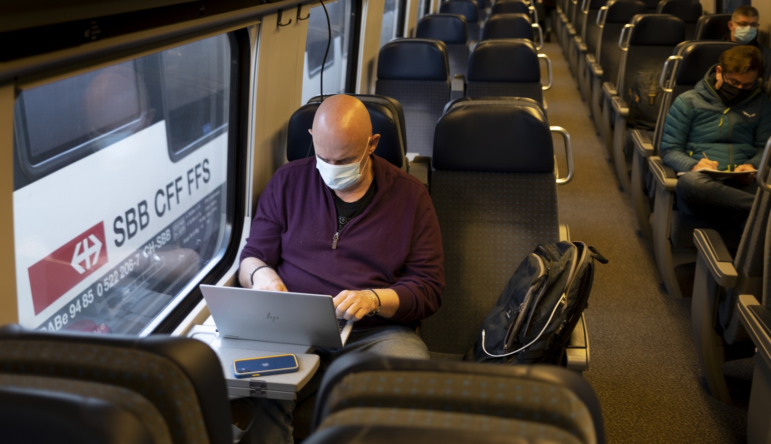 ARCHIV --- ZUR ANKUENDIGUNG DES BUNDESRATS UEBER DIE AUFHEBUNG DER CORONAMASSNAHMEN --- Passenger wearing protective mask works on a laptop as he rides a SBB CFF FFS train during the coronavirus disea ...