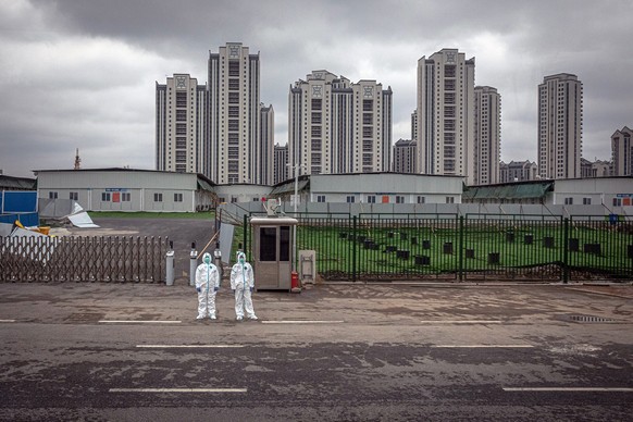 epa08356870 Security wearing full protective gears stand in front of the entrance to Leishenshan Hospital, in Wuhan, China, 11 April 2020. An emergency field hospital Leishenshan was build in ten days ...