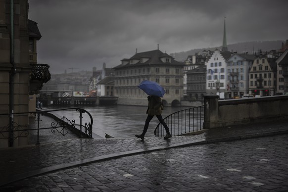 A woman walks in the rain with an umbrella across the Muensterbridge over the river Limmat, on Tuesday, November 21, 2023 in Zurich, Switzerland. (KEYSTONE/Michael Buholzer)