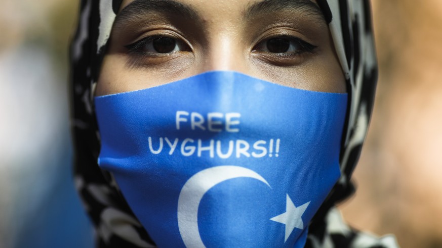 FILE - A woman wears a face mask reading &#039;Free Uyghurs&#039; as she attends a protest during the visit of Chinese Foreign Minister Wang Yi in Berlin, Germany, Tuesday, Sept. 1, 2020. Experts at t ...