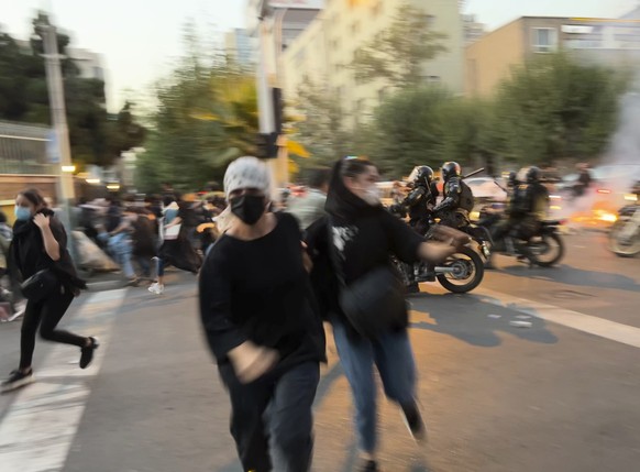 FILE - In this Monday, Sept. 19, 2022, photo taken by an individual not employed by the Associated Press and obtained by the AP outside Iran, women run away from anti-riot police during a protest of t ...