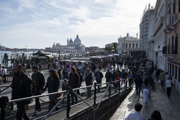 Touristen geniessen das milde Wetter, im Hintergrund die Basilika Santa Maria della Salute, fotografiert am Sonntag, 17. April 2022 in Venedig. (KEYSTONE/Christian Beutler)