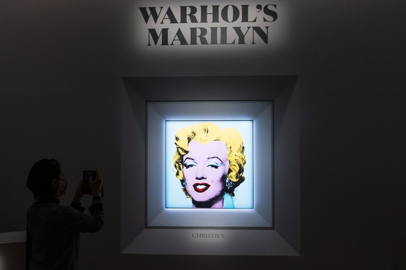 epa09840752 People look at the 1964 painting &#039;Shot Sage Blue Marilyn&#039; by Andy Warhol during a press conference announcing the upcoming auction of the painting at Christie&#039;s in New York, ...