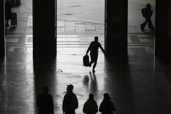 People walk at the train station during a nationwide transport strike, in Milan, Italy, Friday, Nov. 8, 2024. (AP Photo/Antonio Calanni)