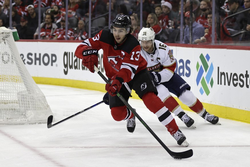 New Jersey Devils center Nico Hischier (13) clears the puck in front of Florida Panthers center Aleksander Barkov during the second period of an NHL hockey game Tuesday, Nov. 9, 2021, in Newark, N.J.  ...