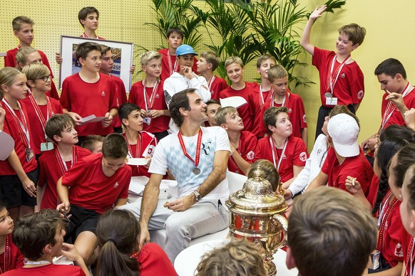 epa06297267 Switzerland&#039;s Roger Federer (C) eats pizza with ball kids after defeating Argentina&#039;s Juan Martin del Potro in their final match of the Swiss Indoors tennis tournament at the St. ...