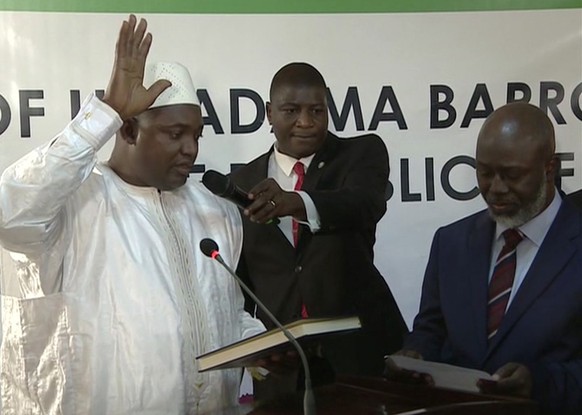 Adama Barrow, left, is sworn in as President of Gambia at Gambia's embassy in Dakar Senegal in this image taken from TV Thursday, Jan 19, 2017. A new Gambian president has been sworn into office in ne ...