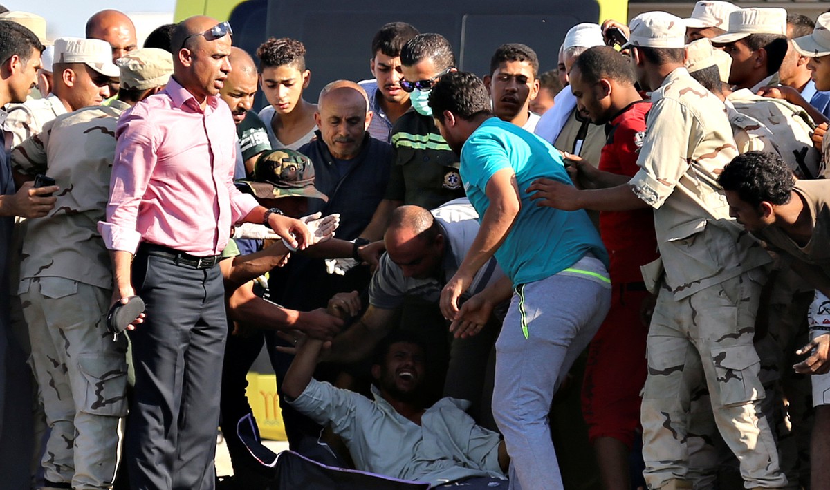 REFILE - CLARIFYING CAPTIONS A man reacts as rescue workers carry the body of a victim on a stretcher after a boat carrying migrants capsized off Egypt's coast, in Al-Beheira, Egypt, September 22 ...