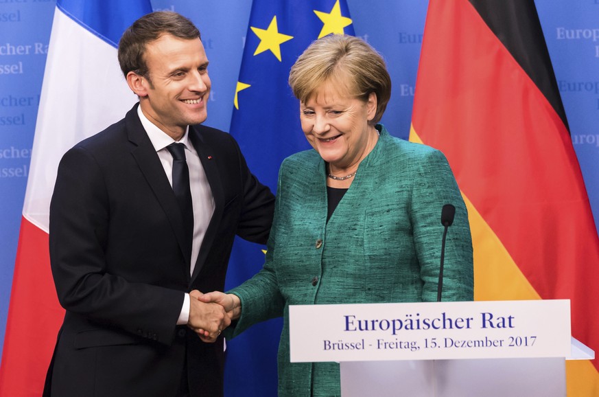 German Chancellor Angela Merkel, right, reaches out to shake hands with French President Emmanuel Macron after addressing a media conference at an EU summit in Brussels on Friday, Dec. 15, 2017. Europ ...