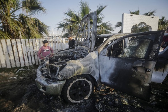 epa11255139 People stand near a destroyed car of the NGO World Central Kitchen (WCK) along Al Rashid road, between Deir Al Balah and Khan Younis in the southern Gaza Strip, 02 April 2024. According to ...