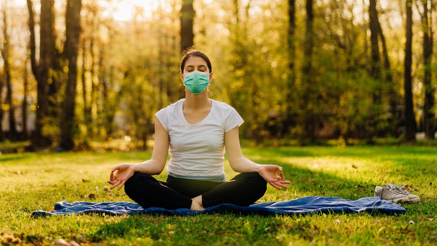 Yoga im Park mit Maske.