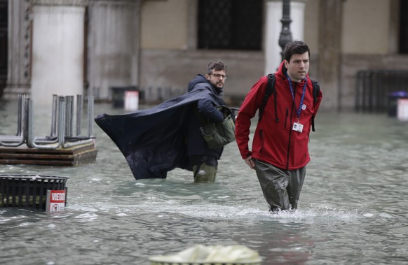 People walk in flooded Venice, Italy, Sunday, Nov. 17, 2019. Venetians are bracing for the prospect of another exceptional tide in a season that is setting new records. Officials are forecasting a 1.6 ...