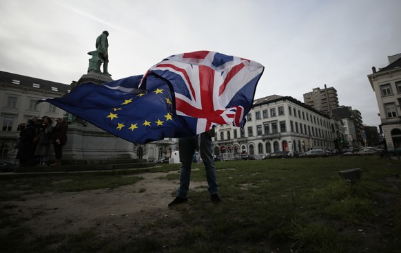 FILE - In this Thursday, Jan. 30, 2020 file photo, Pro-EU supporter Peter Cook unfurls a Union and EU flag prior to a ceremony to celebrate British and EU friendship outside the European Parliament in ...