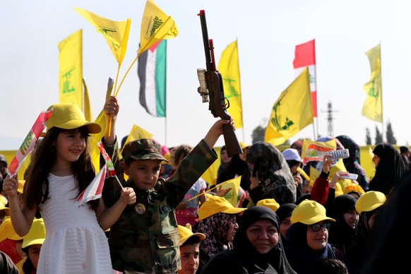 epa05481080 Children wave Hezbollah flags and hold replica toy guns as they listen to the speech of Hezbollah leader Hassan Nasrallah via a giant screen during the &#039;Victory Festival&#039; to mark ...