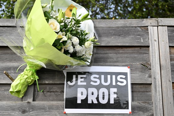 FILE - Flowers next to a placard reading &quot;I am a teacher&quot; in tribute to Samuel Paty, the history-geography teacher who was beheaded on Oct. 16, 2020, are pictured near the Bois d&#039;Aulne  ...