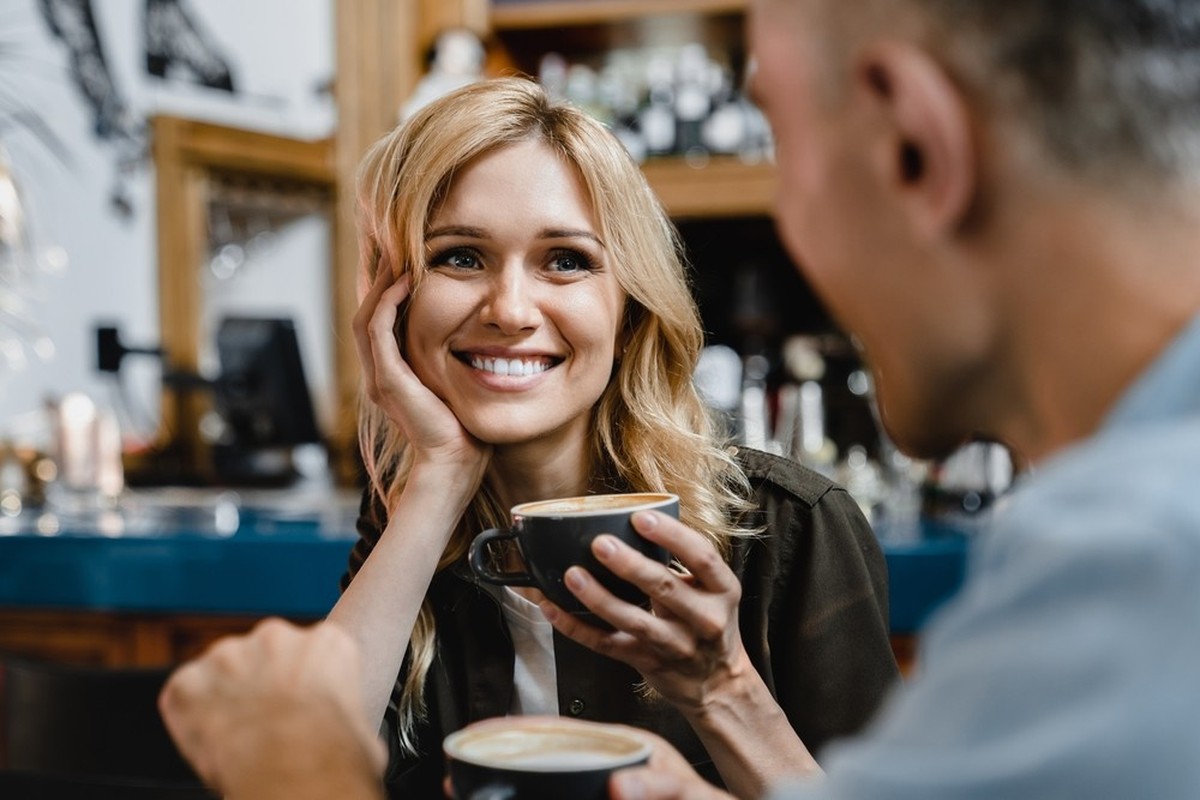 Interessierte aufgeregt, sich in die verliebte reife Frau zu verlieben, die ihrem Mann Freund zuhört, während sie Kaffee im Restaurant Café zu einem Date trinken