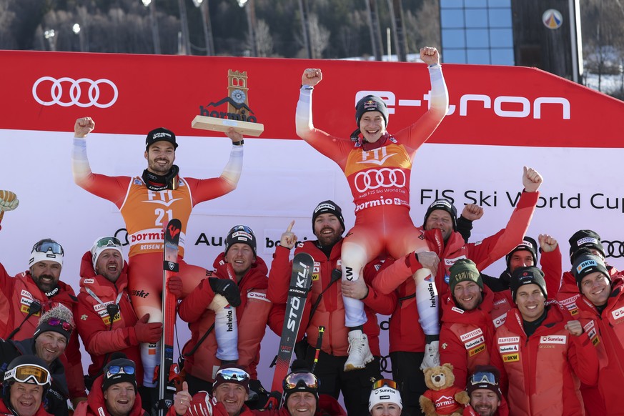 Switzerland's Marco Odermatt, right, winner of an alpine ski, men's World Cup Super G race, and third-placed Switzerland's Loic Meillard celebrate with the team, in Bormio, Italy, Thurs ...