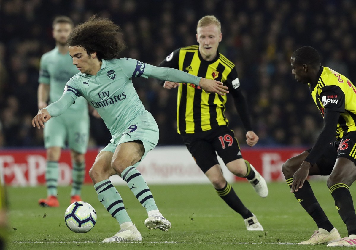 Arsenal's Matteo Guendouzi controls the ball in front of Watford's Will Hughes and Abdoulaye Doucoure, right, during the English Premier League soccer match between Watford and Arsenal at Vi ...