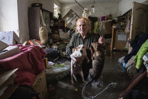 Local resident Tetiana holds her pets, Tsatsa and Chunya, as she stands inside her house that was flooded after the Kakhovka dam blew up overnight, in Kherson, Ukraine, Tuesday, June 6, 2023. Ukraine  ...