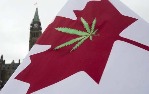 FILE - In this April 20, 2015 file photo, a Canadian flag with a cannabis leaf flies on Parliament Hill during a 4/20 event in Ottawa, Ontario. Another big first for the marijuana industry is in the b ...