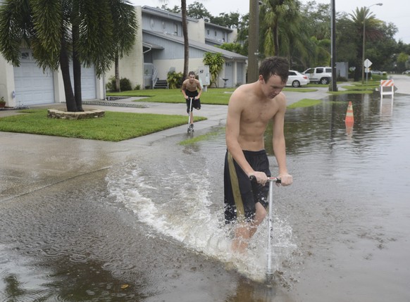 Ethan Deming, 15, left, and Jake Kennedy, 16, race their scooters into a flooded South Lagoon Street in Tampa, Fla., on Sept. 1, 2016. Rain and a high tide combined to raise the water level several in ...