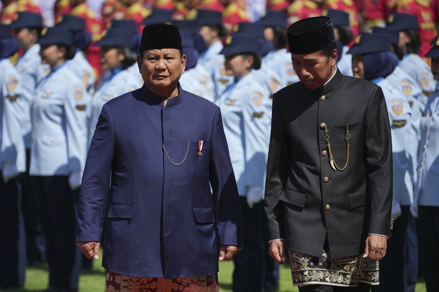 Indonesia&#039;s newly-inaugurated President Prabowo Subianto, left, walks with his predecessor Joko Widodo as they inspect honor guards during their handover ceremony at Merdeka Palace in Jakarta, In ...