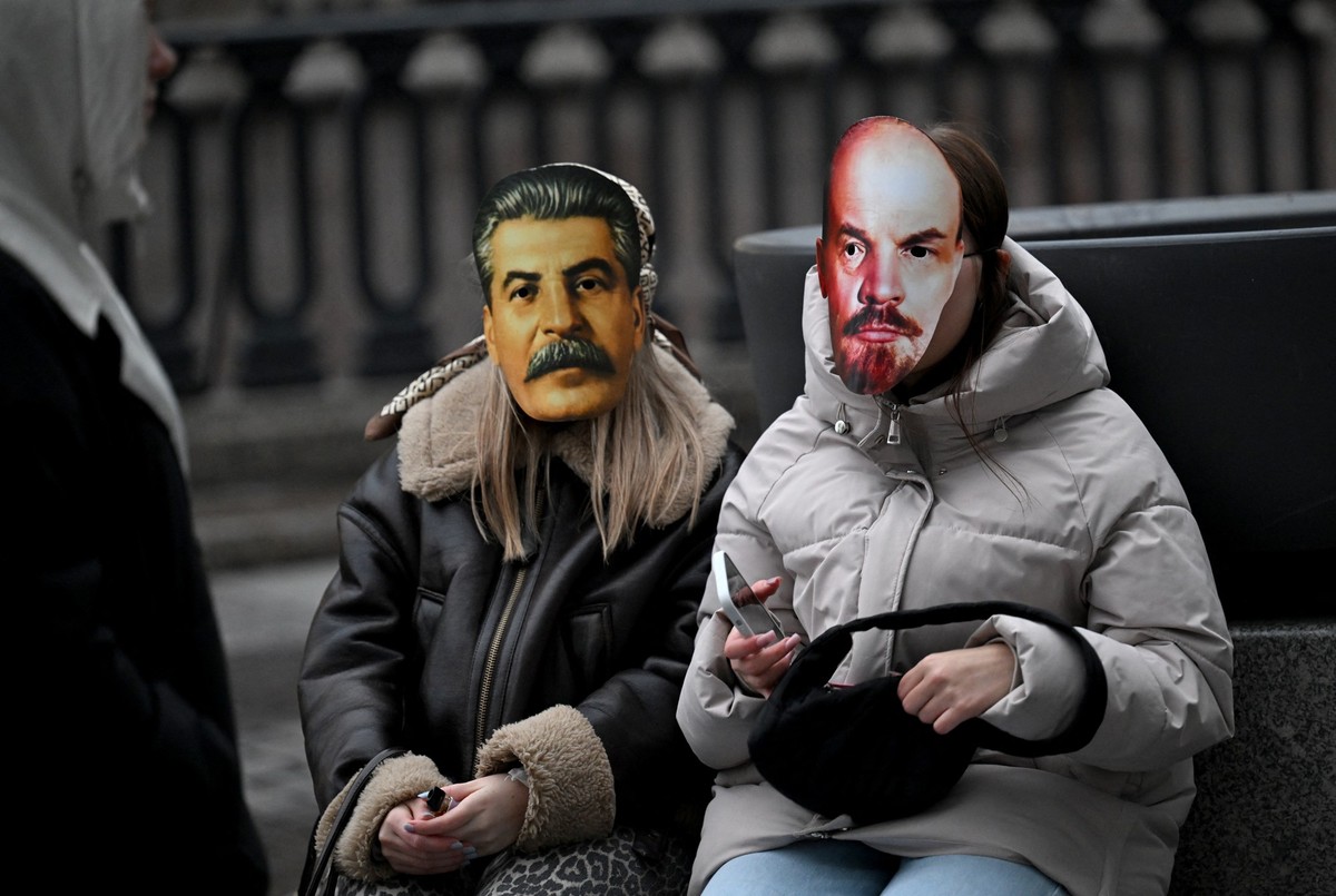 Young women wearing masks of Soviet dictator Josef Stalin and Soviet state founder Vladimir Lenin attend a street musicians' concert in the center of Saint Petersburg on October 27, 2025.