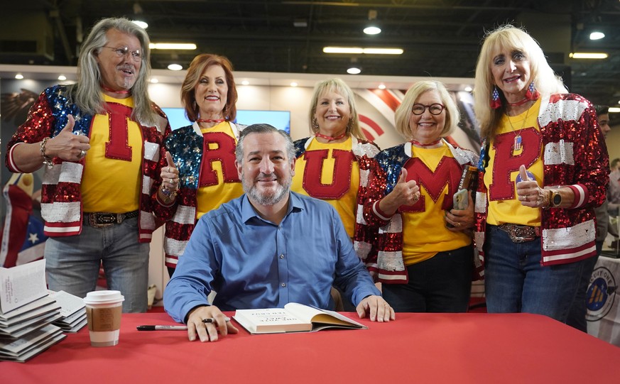 Supporters of former President Donald Trump line up behind Sen. Ted Cruz, R-Texas, to pose for photos during a book signing at the Conservative Political Action Conference (CPAC) in Dallas, Friday, Au ...