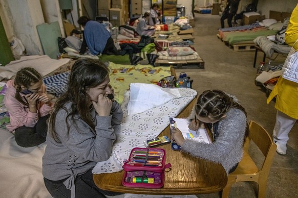 epa09794358 A woman looks at a child painting as they stay in Ohmadyt children's hospital basement used as a shelter for protection against airstrikes, in Kyiv (Kiev), Ukraine, 01 March 2022. Rus ...