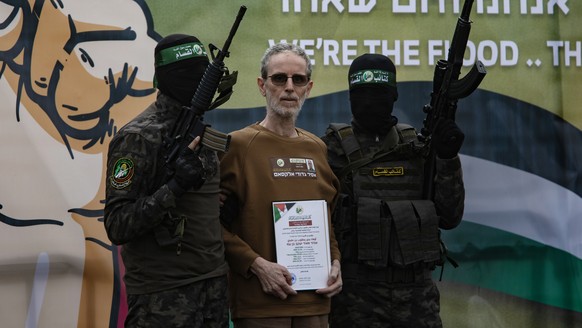 epaselect epa11882145 Palestinian fighters from Hamas&#039;s Izz ad-Din al-Qassam Brigades escort Israeli hostages Ohad Ben-Ami (pictured), Or Levi and Eli Sharabi onto the stage before handing them o ...