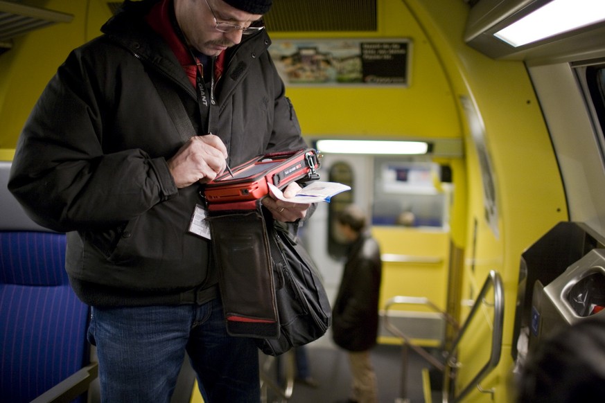 A civilian inspector checks the validity of a season ticket with his specialized portable computer in the S3 train on the way between Zurich and Lenzburg, Switzerland, during a top priority check of t ...