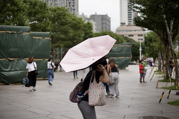 epa10839462 A woman reacts to a strong wind in the aftermath of Typhoon Haikui in Taipei, Taiwan Sept. 4, 2023. Southern Taiwan faces power outages due to Typhoon Haikui, which knocked down tree and ...