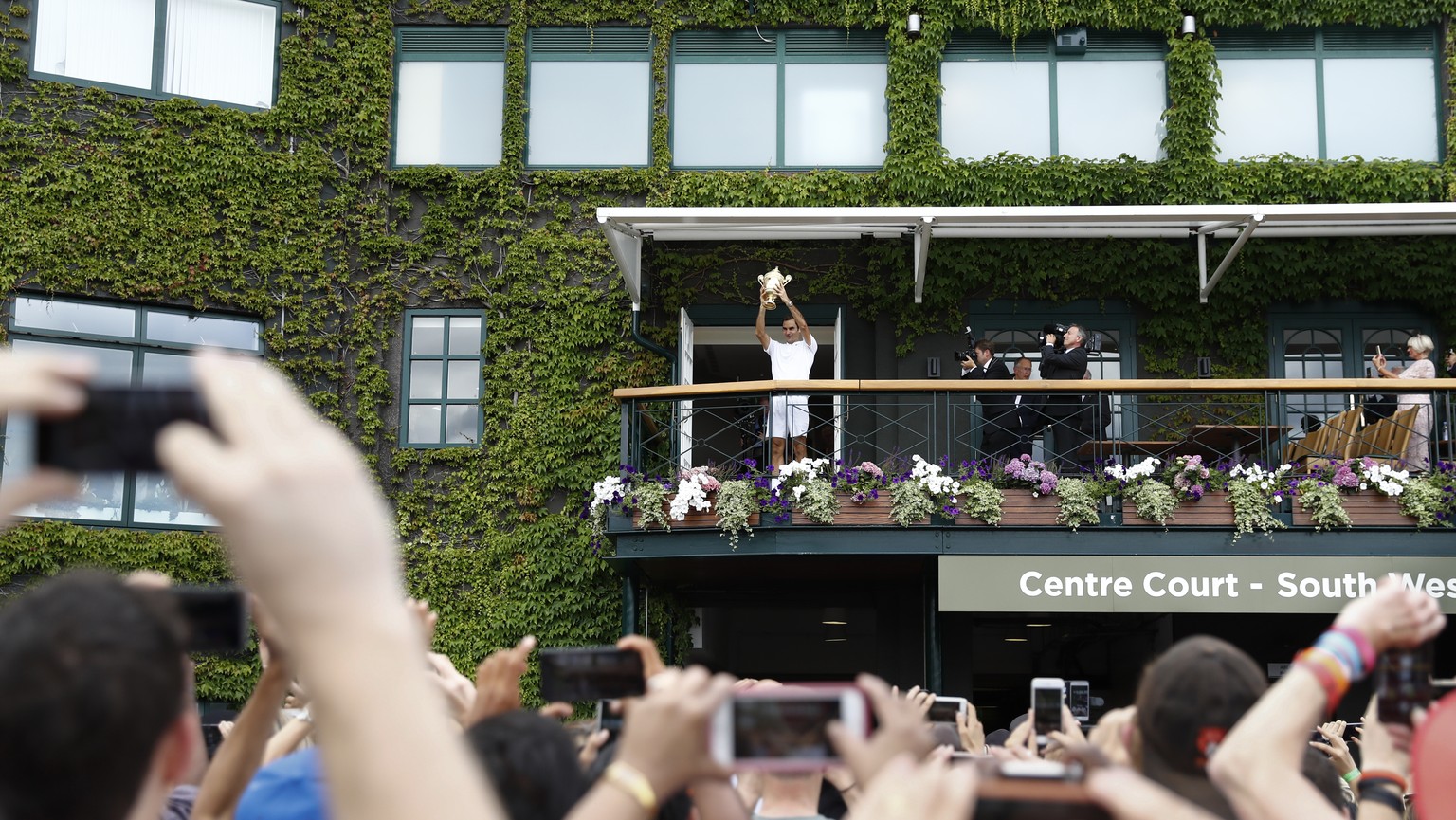 Roger Federer of Switzerland celebrates with the trophy on the balcony of the centre court after winning the men&#039;s final match against Marin Cilic of Croatia during the Wimbledon Championships at ...