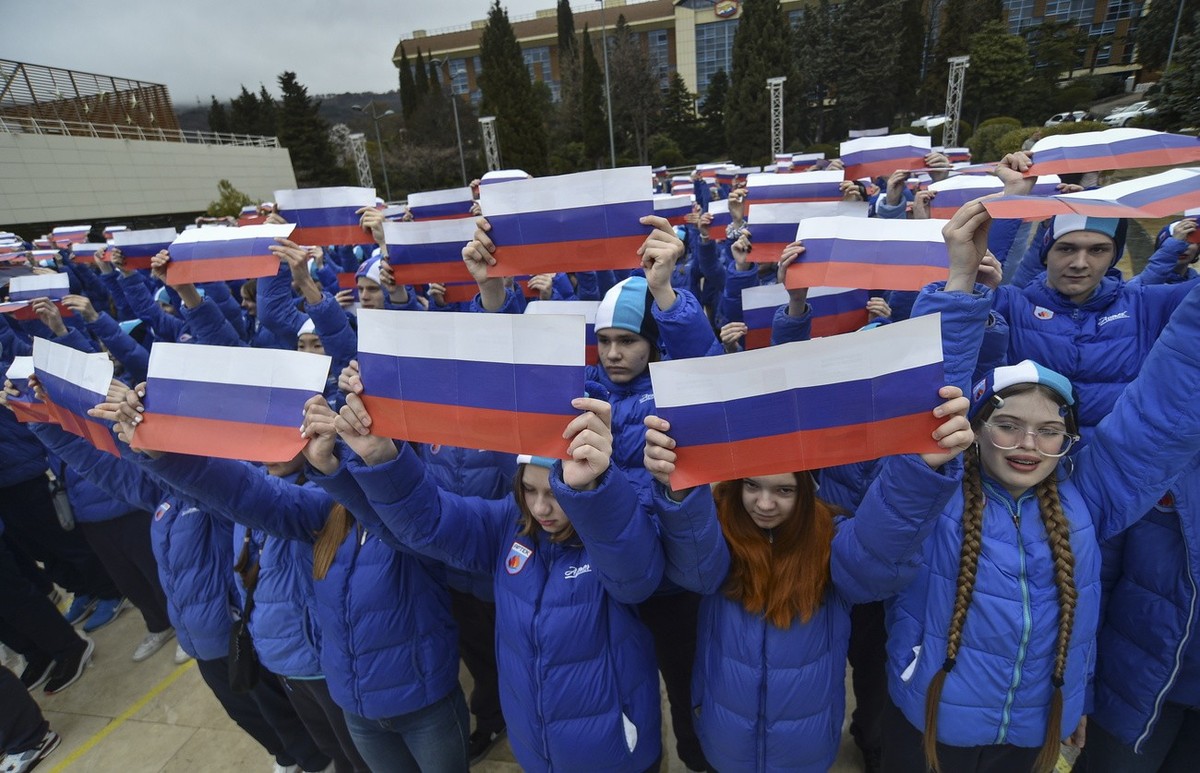 epa10524586 Youths hold Russian national flags during the 'Crimean spring - nine years together' rally-concert at the International Child Centre 'Artek' in Gurzuf, Crimea, 15 March ...
