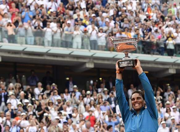 epa06799190 Rafael Nadal of Spain celebrates with the trophy after winning his 11th French Open title against Dominic Thiem of Austria during their men’s final match during the French Open tennis tour ...