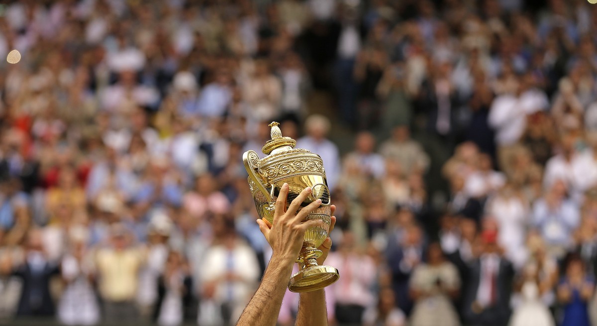 FILE - Switzerland's Roger Federer celebrates with the trophy after beating Croatia's Marin Cilic in the Men's Singles final match on day thirteen at the Wimbledon Tennis Championships  ...