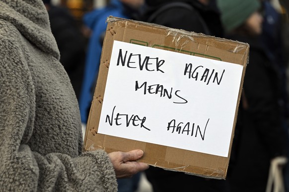 epa11197076 A person holds a placard as people gather in Helvetiaplatz during a rally against anti-Semitism, one day after a Jewish man was stabbed, in Zurich, Switzerland, 03 March 2024. People carri ...