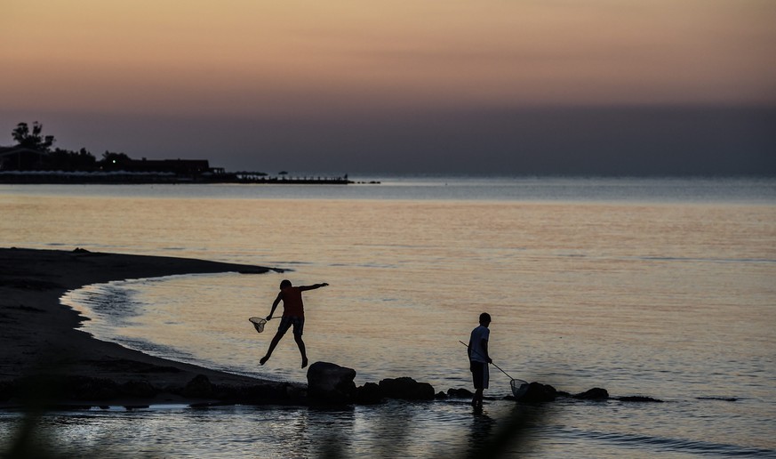 epa04865487 A young boy jumps as he enjoys fishing during a hot evening at the beach of Rhoda, Corfu, Greece, 29 July 2015. Meteorologist predict warm temperatures of up ton31 Celsius within the next  ...