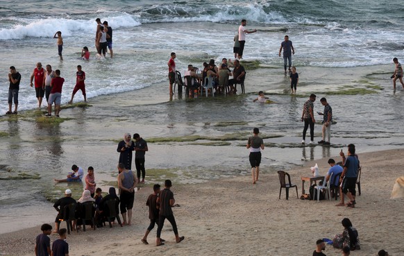 Palestinians sit as they enjoy the beach of the Deir el-Balah refugee camp by the Mediterranean Sea, central Gaza Strip, Friday, Aug. 20, 2021. (AP Photo/Adel Hana)