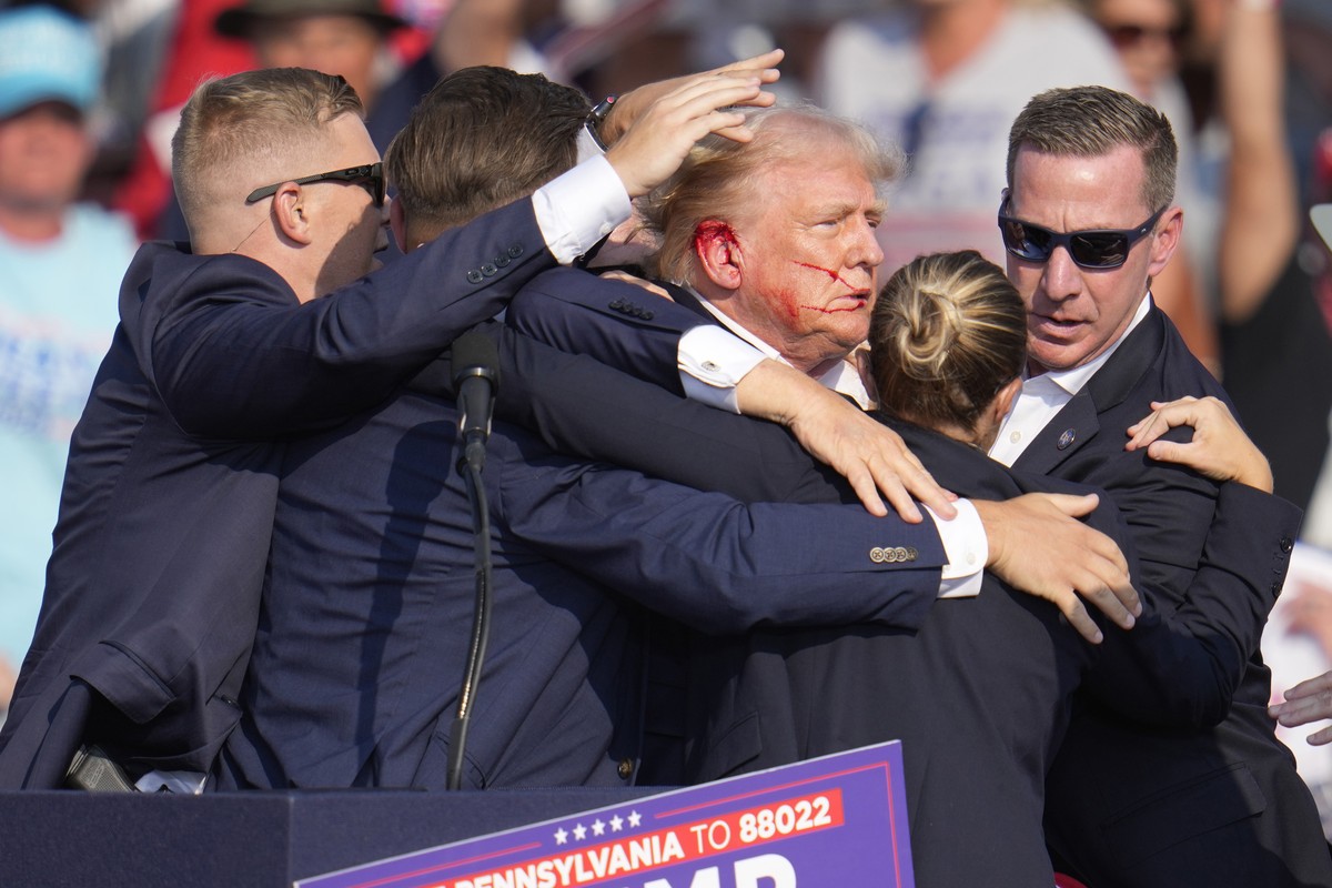 Republican presidential candidate former President Donald Trump is surrounded by U.S. Secret Service agents as he is helped off the stage at a campaign rally in Butler, Pa., Saturday, July 13, 2024. ( ...